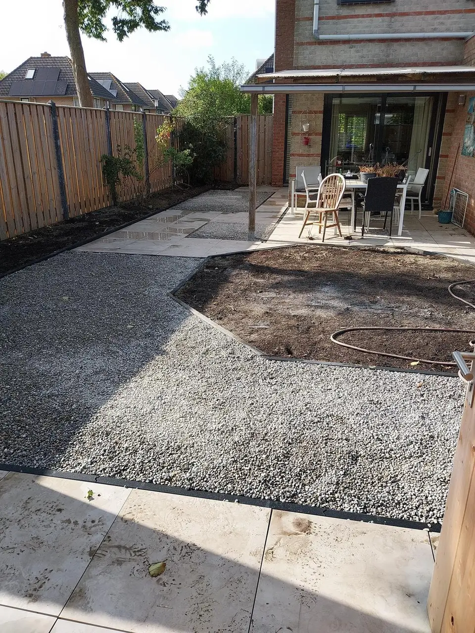 Achtertuin voor de verbouwing, met kaal zand en oude bestrating