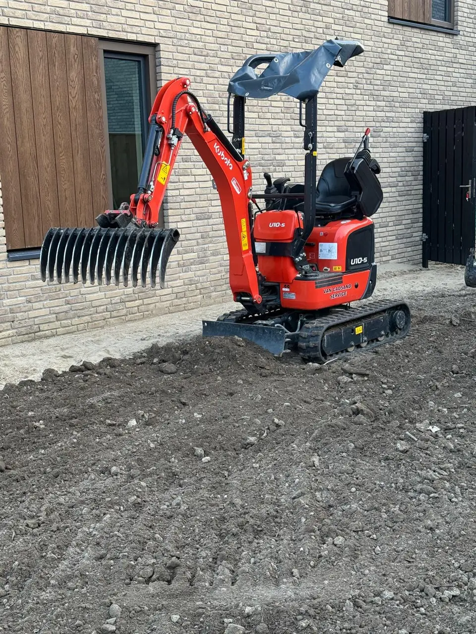 Minikraan trekt de grond los en brengt hem op hoogte