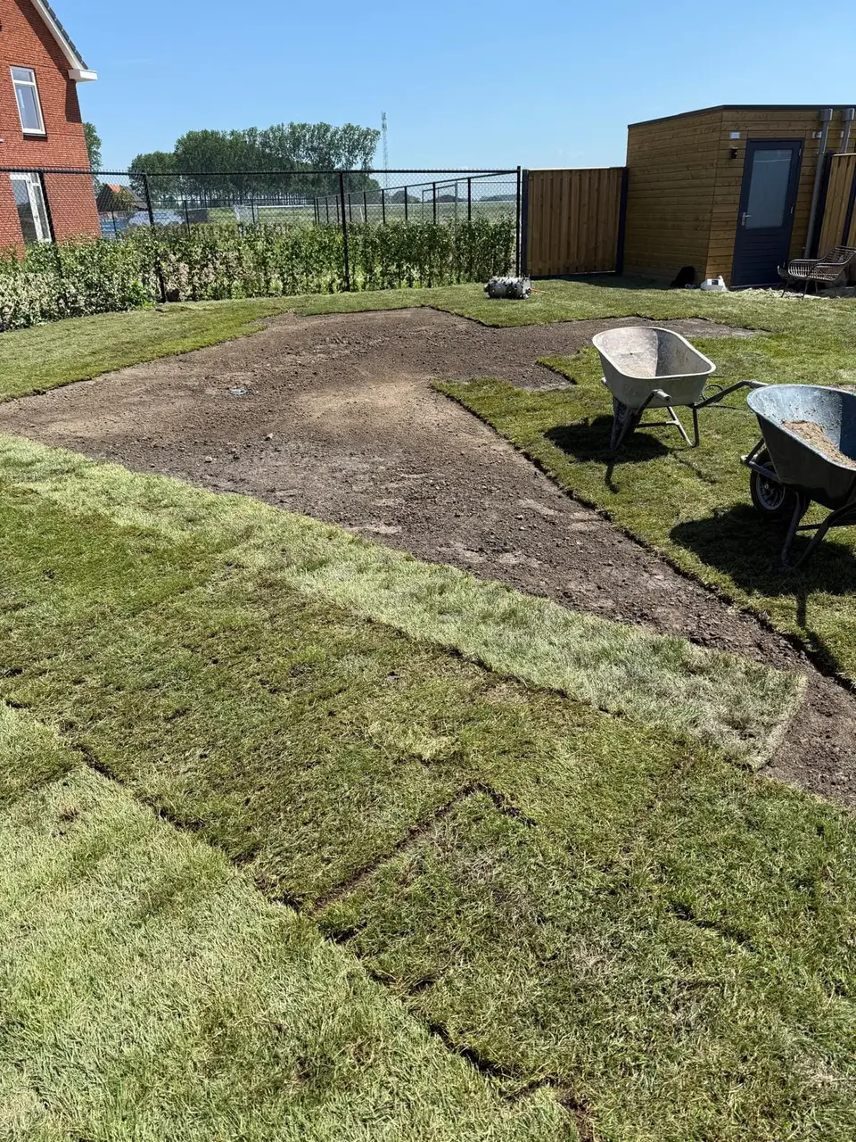 De eerste graszoden worden gelegd op de voorbereide ondergrond
