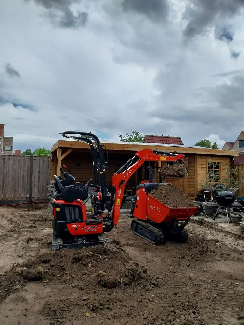 Minikraan met rupsdumper aan het werk in de tuin