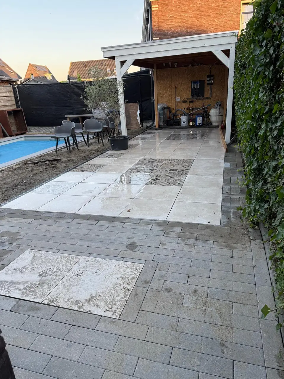 Terras met grote tegels en sierbestrating onder de overkapping