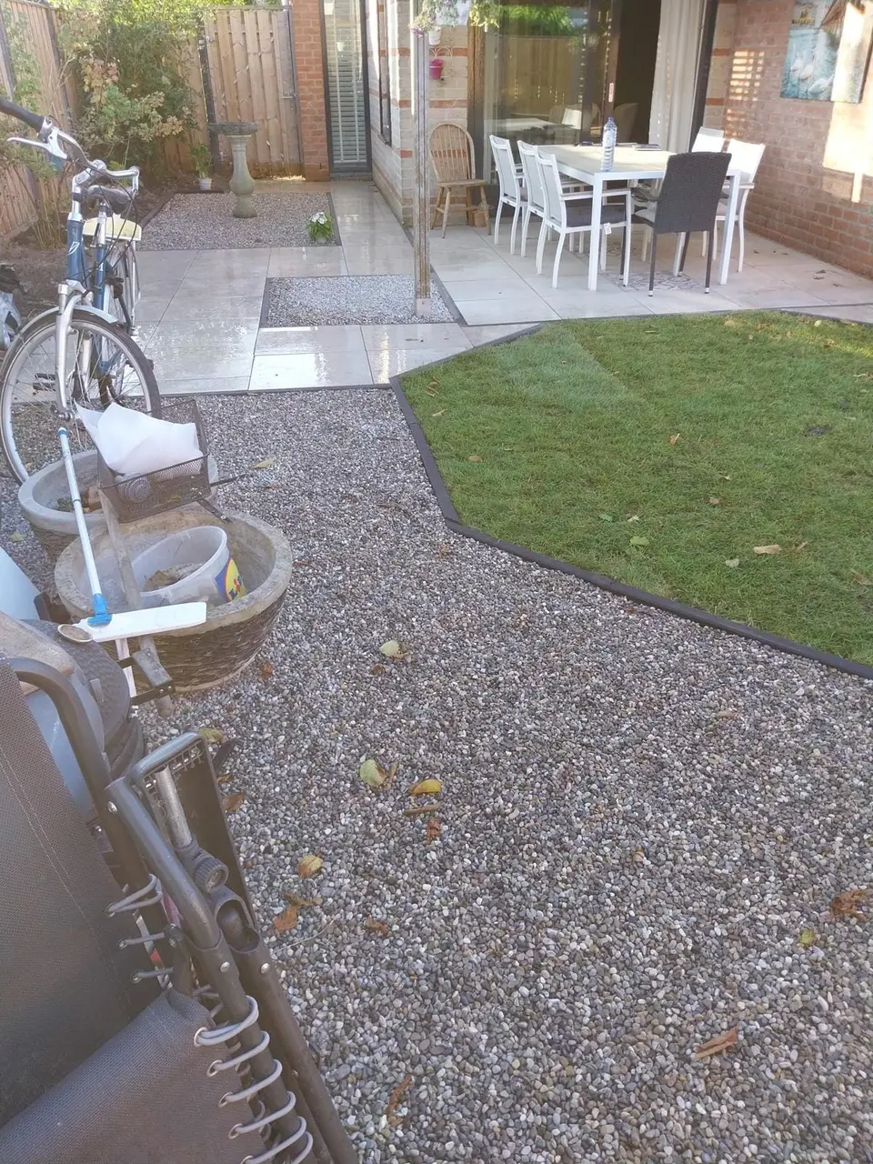 Overzicht van de afgewerkte tuin met terras, gazon en grind